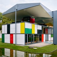 Modernes Gebäude mit bunten Fassadenpaneelen und grossen Fenstern im Grünen.