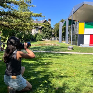 Frau fotografiert modernes Gebäude im Park bei Sonnenschein.