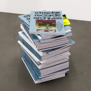 Stapel blauer Bücher auf dem Boden.