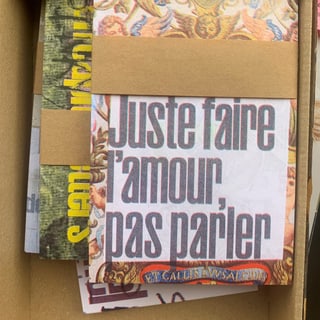 Schachtel mit Papieren, 'Juste faire l'amour, pas parler' vorne sichtbar.
