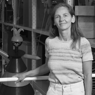 Frau steht neben einer grossen Skulptur in einem Regalraum.