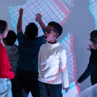 Kinder tanzen vor farbigen Lichtprojektionen.