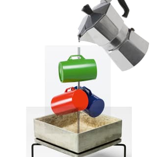 Espressokanne giesst Kaffee in bunte Tassen auf Ständer.