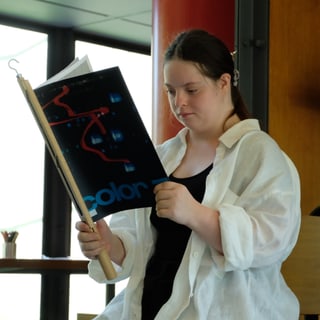 Frau sitzt und liest ein Buch drinnen.