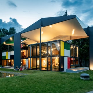 Modernes zweistöckiges Gebäude mit grossem Dach bei Abenddämmerung.