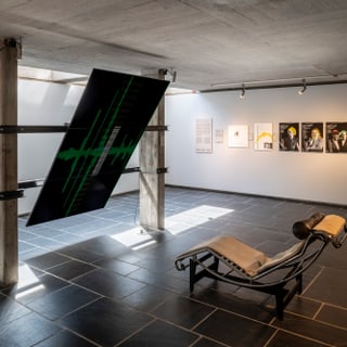Innenraum mit Liegestuhl und Kunstwerken an den Wänden.