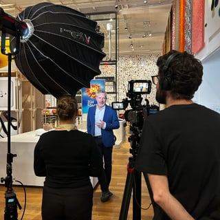Dreharbeiten in einer Galerie mit einem Interviewer und Kameraleuten.