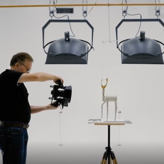 Mann fotografiert Modell im Studio mit Beleuchtung.