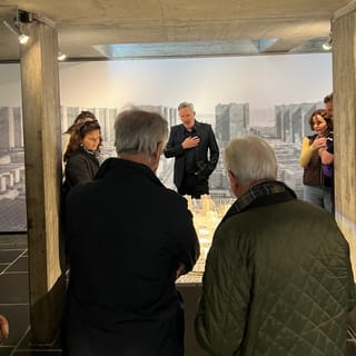 Menschen betrachten ein Architekturmodell in einem Ausstellungsraum.