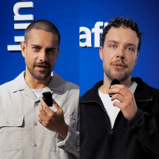 Zwei Männer vor blauem Hintergrund, halten Mikrofone.