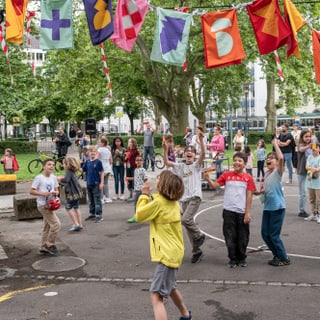 Kinder spielen auf der Strasse unter bunten Wimpeln beim Projektauftakt von Museumjung.