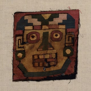 Textiles Fragment mit geometrischem Gesichtsmuster.