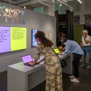 Menschen interagieren mit Laptops im Ausstellungsraum.
