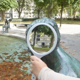 Statue im Park, jemand hält einen Handspiegel vor dessen Kopf.