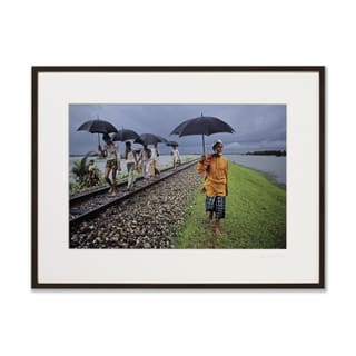 Menschen mit Regenschirmen gehen auf Bahngleisen.