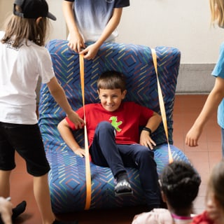 Kinder spielen auf einem grossen selbstgebastelten Stuhl.