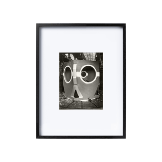 Black and white photograph in black frame, industrial object with openings.