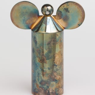 Metallische Skulptur mit runden Ohrenform und Kugel oben.