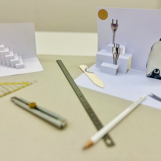 Papierkunst mit Pinguin und Treppe, Werkzeuge auf Tisch.