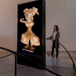 Person betrachtet Skulptur in Museumsvitrine.