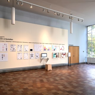 Museumsausstellung im Vestibül mit Zeichnungen an der Wand und Computerstation.