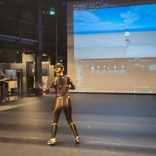 Person im Motion-Capture-Anzug vor Bildschirm mit 3D-Simulation.