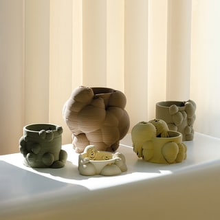 Mehrere organisch geformte Keramiktöpfe auf Fensterbank vor Jalousien.