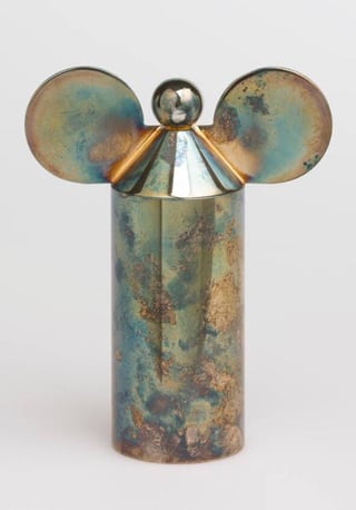 Metallic sculpture with cylindrical body and round ears.