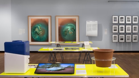 Ausstellungsraum mit modernen Kunstwerken an Wänden und Tischen.