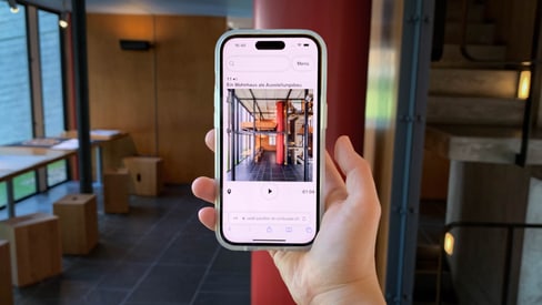 Hand hält Smartphone mit dem eGuide in modernem Innenbereich.