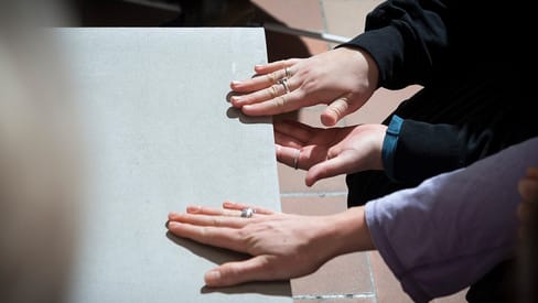 Zwei Personen legen ihre Hände auf eine Steinplatte.