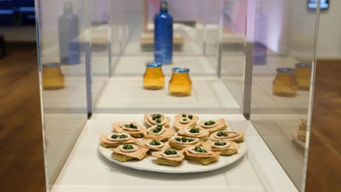 Ausstellung mit Teller mit Vorspeisen und Glasflaschen im Hintergrund.