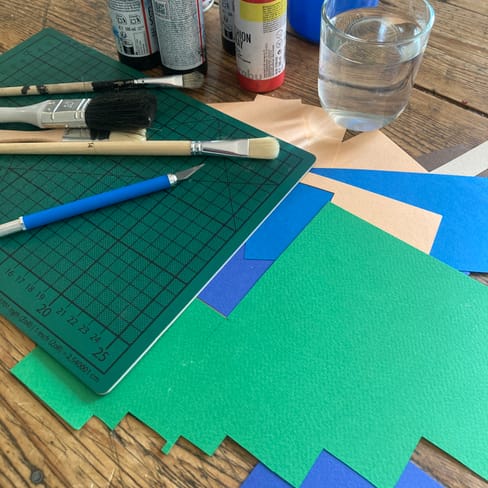 Kunstbedarf auf einem Tisch, einschliesslich Malutensilien und Papier.