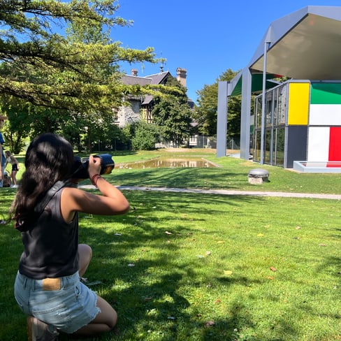 Frau fotografiert modernes Gebäude im Park bei Sonnenschein.