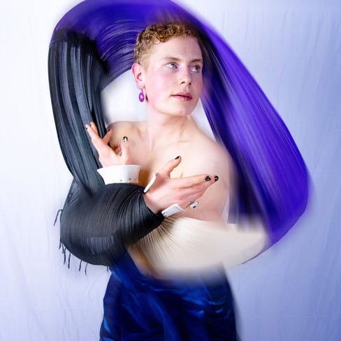 Person in künstlerischer Pose mit buntem Stoff umwickelt.