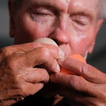 Älterer Mann hält Bälle in der Hand nah am Gesicht.