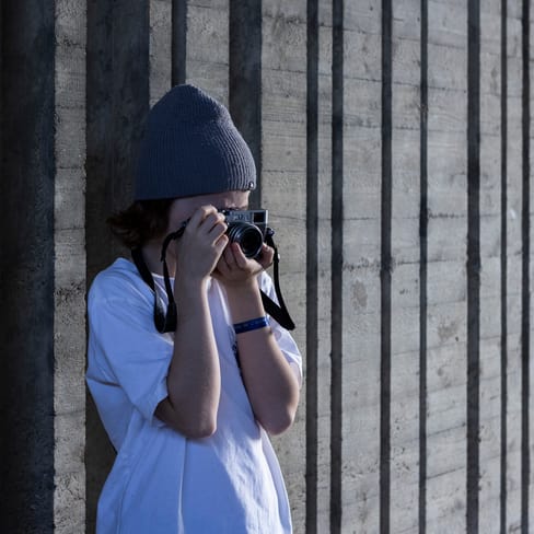 Person mit Mütze fotografiert an Betonwand.