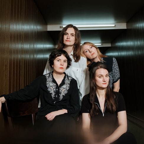 Vier Personen in einem Flur mit Holzverkleidung.