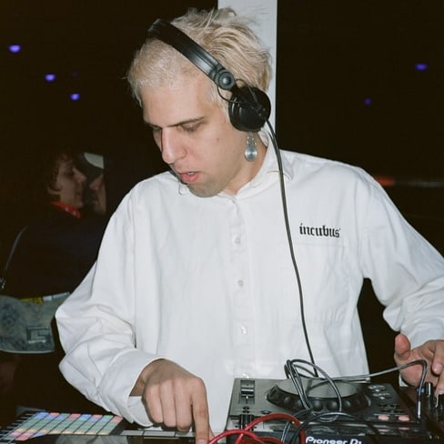 Person mit Kopfhörern spielt Musik an DJ-Pult.