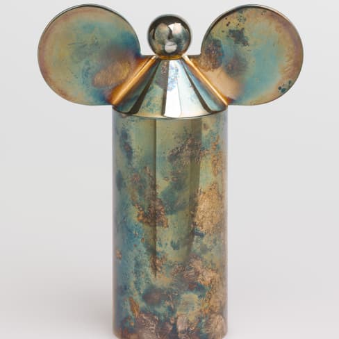 Metallische Skulptur mit runden Ohrenform und Kugel oben.