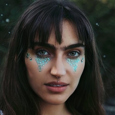 Frau mit blauem Glitzer-Make-up im Gesicht im Freien.