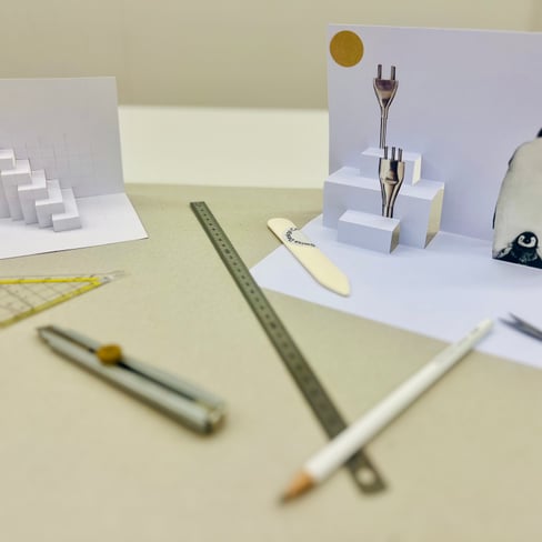 Papierkunst mit Pinguin und Treppe, Werkzeuge auf Tisch.