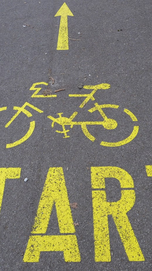 Gelbes Fahrrad-Symbol und 'START' auf Asphalt.",