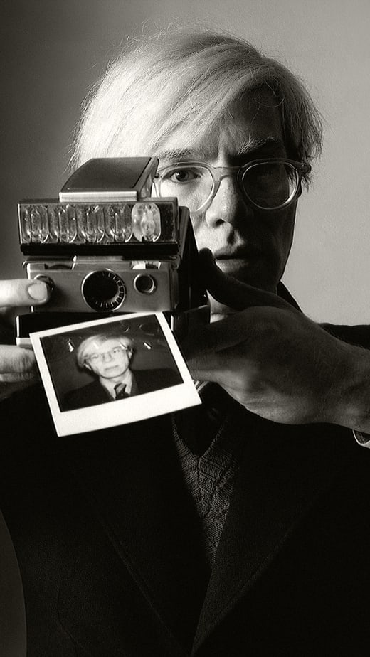 Schwarzweissfoto einer Person, die ein Polaroid-Foto hält.