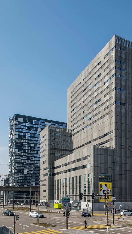 Moderner Bürogebäudekomplex mit Strassenszene und blauem Himmel.