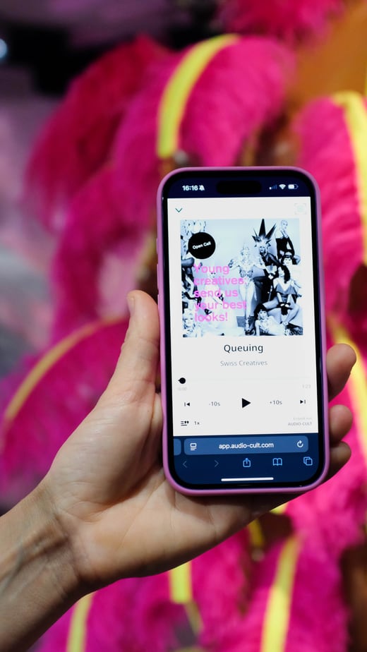 Hand hält Smartphone mit Musik-App vor leuchtend rosa Kostüm.