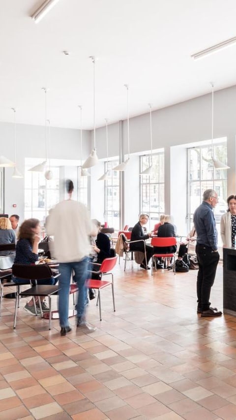 Menschen in einem Café mit Getränken und Gebäck in der Vitrine.