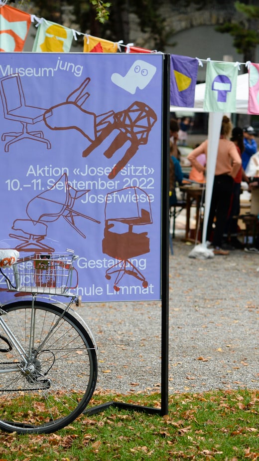 Fahrrad vor Plakat des museumjung auf einer Veranstaltung im Freien.