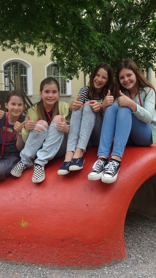 Vier Mädchen sitzen auf einer roten Skulptur auf einem Spielplatz.