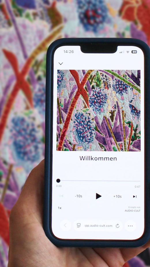 Hand hält Smartphone vor farbigem Blumengemälde.